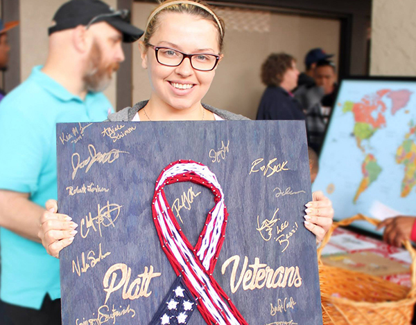PCSD VA Student holding U.S.A. flag ribbon on chalkboard for VA students to sign.